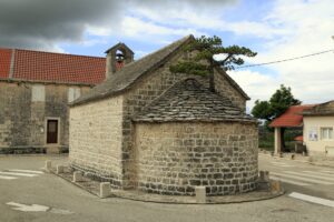 Apsida kostola svätého Petra s borovicou na streche v Nerežišćach